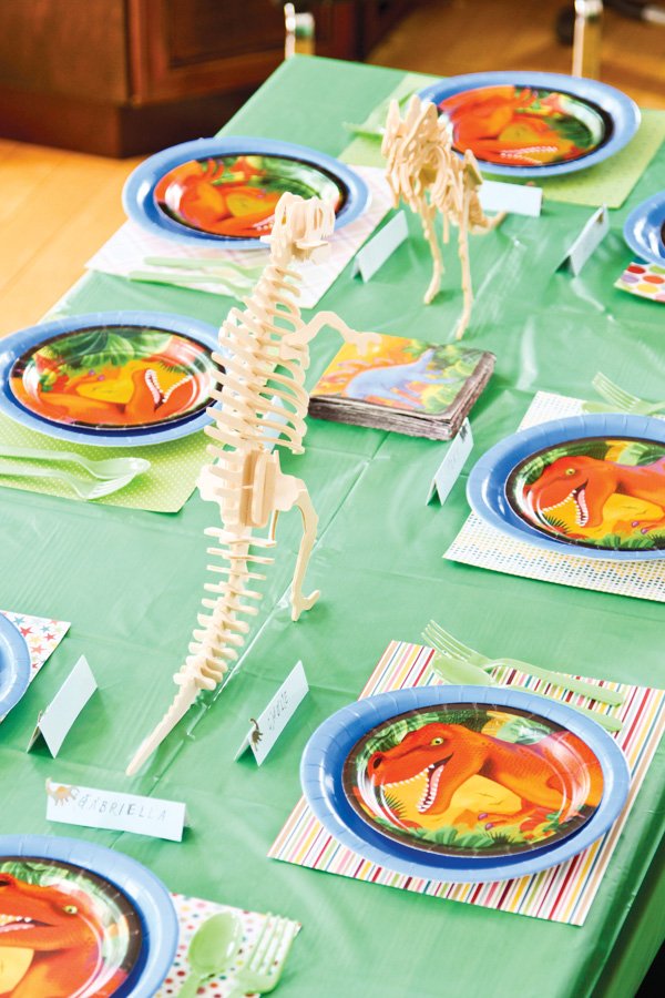 dinosaur party table setting with wooden dino skeleton centerpieces
