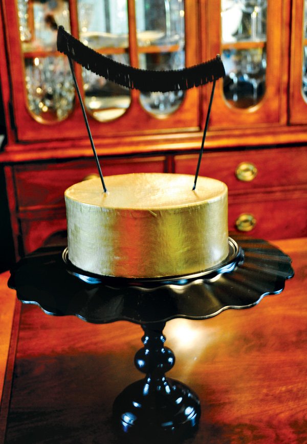gold cake with a black fringe bunting cake topper