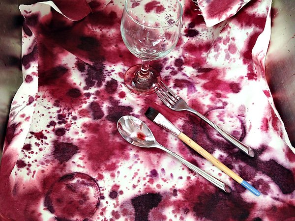 Step two of the wine-splattered napkins DIY tutorial is to dip the bottom of a wine glass into the dye and stamp onto the napkins to create wine rings