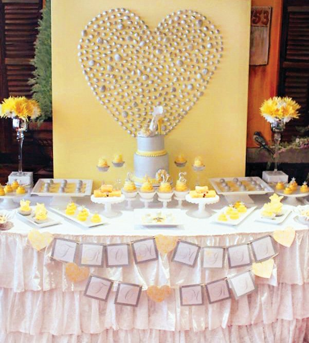 yellow and gray dessert table with a silver seashell heart backdrop