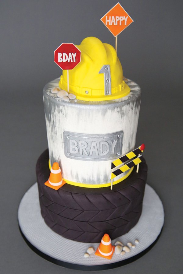 construction first birthday party cake with hard hat topper, road signs and tire layer