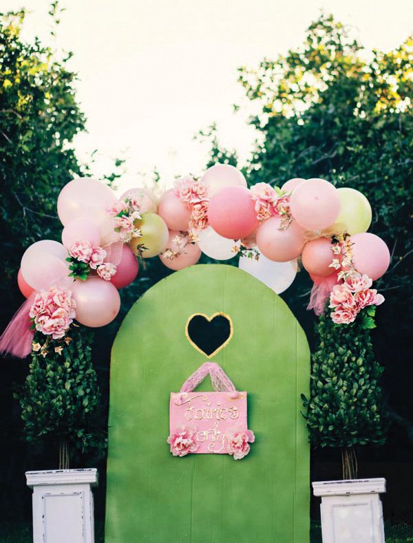 diy pink balloon and flower arch over a cardboard doorway