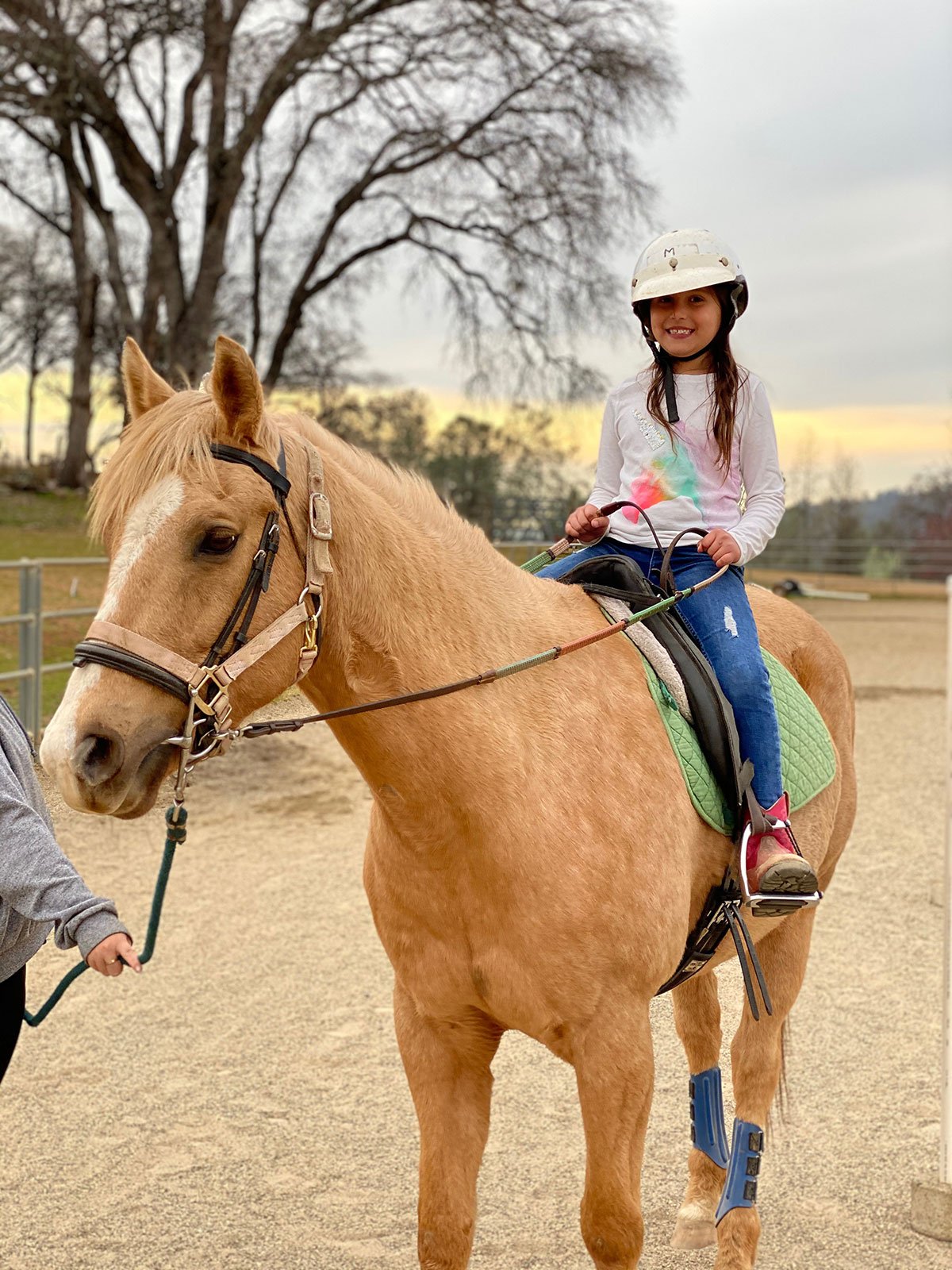 young girl riding a tan horse