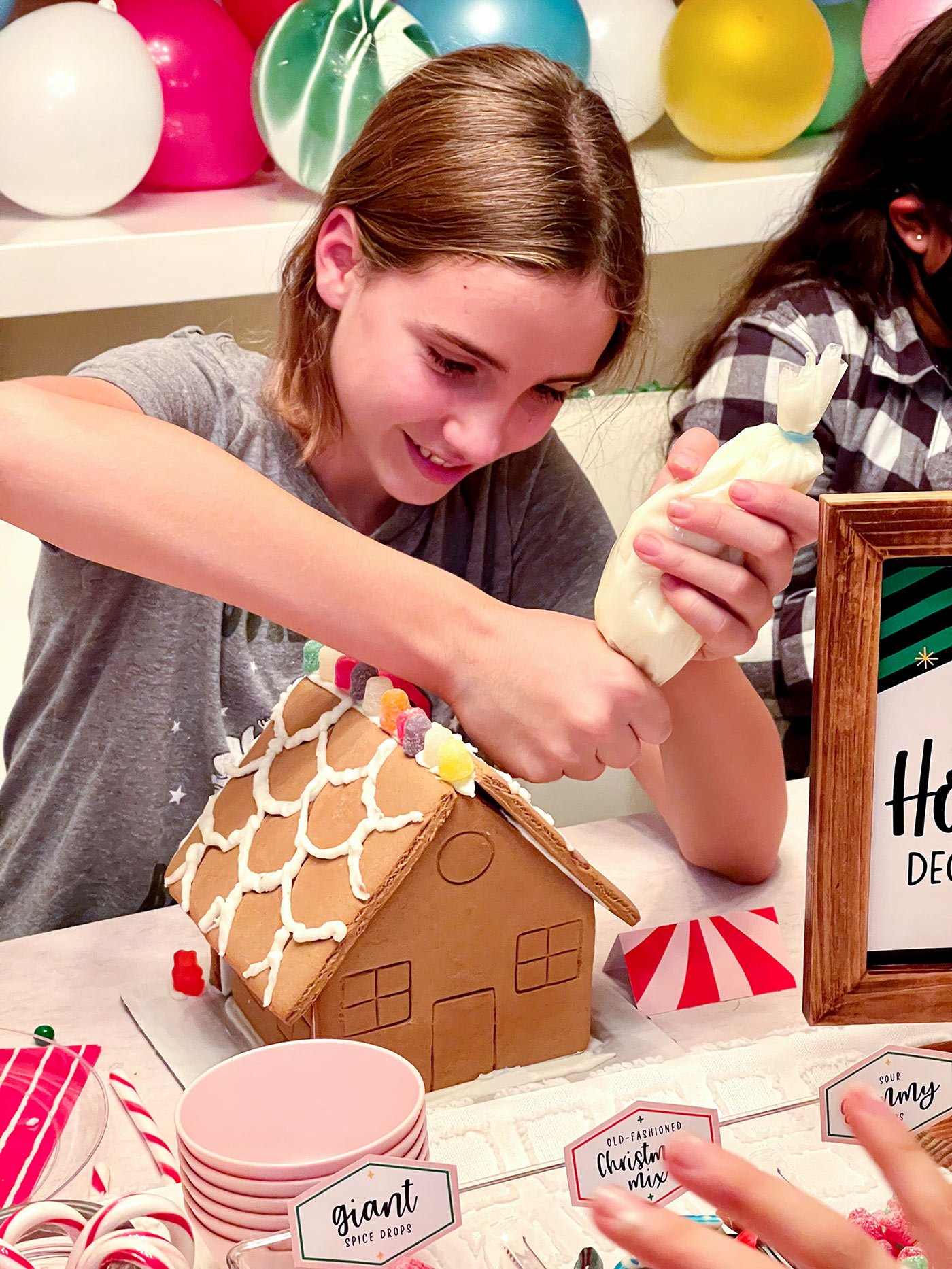 girl decorating a christmas gingerbread house